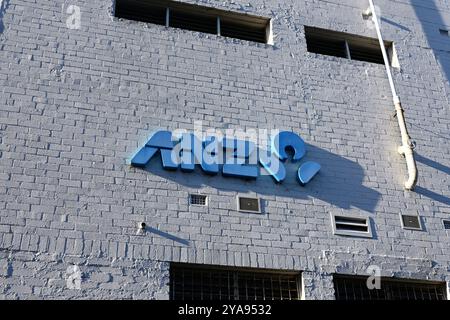 Blue ANZ Bank logo on the white painted brick wall of a suburban branch late in the afternoon, the logo casting a shadow across the wall Stock Photo