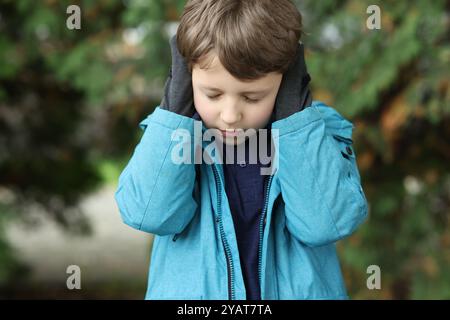 Autism concept. Lonely little boy covering his ears outdoors Stock Photo