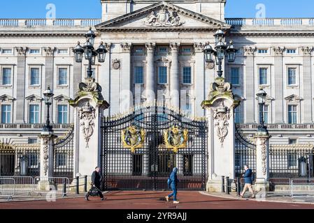 London, UK - March 27, 2024: Men walking near the gates of Buckingham Palace in London, United Kingdom. Stock Photo