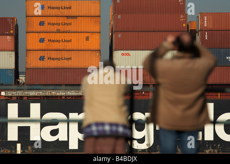 Shipping spotters train binoculars on a Hapag-Lloyd container cargo ship navigating downstream on the River Thames Stock Photo