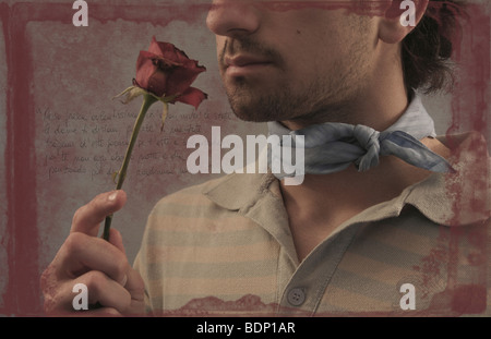 A young man wearing a scarf holding a red rose Stock Photo