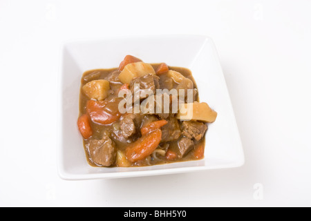 Beef stew or Goulash in white bowl isolated against white background. Stock Photo