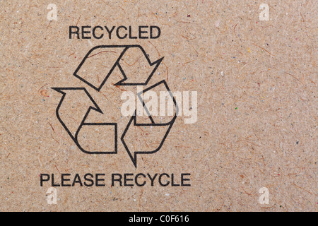 Close up photo of the recycle symbol printed on a recycled cardboard background. Stock Photo