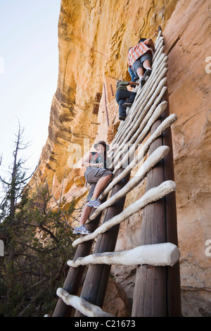 A woman poses for a picture on a ladder leading up to Balcony House cliff dwelling in Mesa Verde National Park, Colorado, USA. Stock Photo