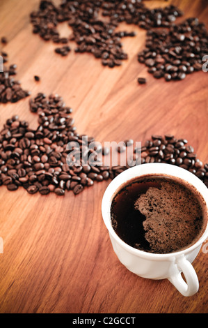 Dramatic photo of world map made of coffee beans. White cup with hot drink. Stock Photo