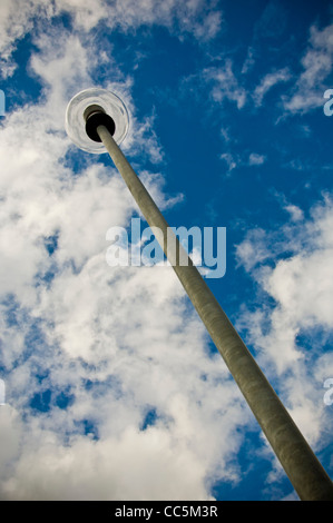 Modern metal street light shot from a low angle looking up towards a blue sky with white clouds Stock Photo