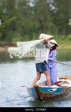 A fisherman swings his large weighted net round his head and into the waters of the Thu Bon River near Hoi An in Vietnam. Stock Photo