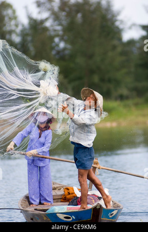 A fisherman swings his large weighted net round his head and into the waters of the Thu Bon River near Hoi An in Vietnam. Stock Photo