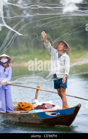 A fisherman swings his large weighted net round his head and into the waters of the Thu Bon River near Hoi An in Vietnam. Stock Photo