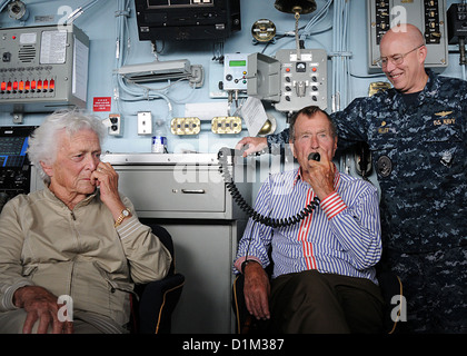 Former President George H. W. Bush, center, addresses U.S. Sailors using the public address system during a visit to the aircraft carrier USS George H. W. Bush (CVN 77) in the Atlantic Ocean Jan. 14, 2010. Accompanying Bush are wife Barbara Bush, left, an Stock Photo