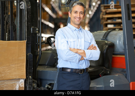 Portrait Of Man With Fork Lift Truck In Warehouse Stock Photo