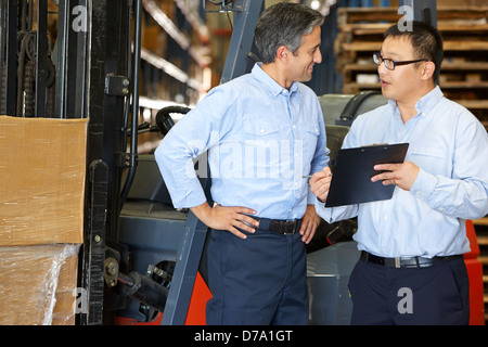 Businessmen Meeting By Fork Lift Truck In Warehouse Stock Photo