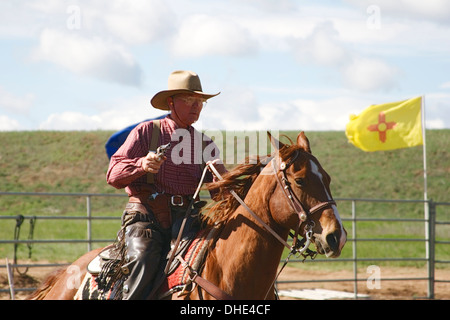 Cowboy with gun on horse and New Mexico flag, mounted shooting competition, End of Trail Wild West Jubilee, Albuquerque, NM USA Stock Photo