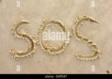 SOS 'Save Our Souls' sign symbol drawn in beach sand Stock Photo