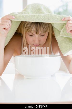 Woman inhaling steam from bowl Stock Photo