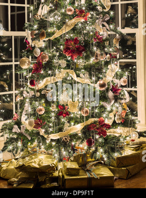 Christmas tree with lights and decorations and Christmas presents underneath in a house living room Stock Photo