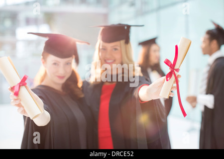 Smiling graduates holding diplomas Stock Photo