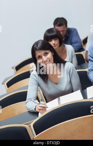 Smiling woman looking up from note taking Stock Photo