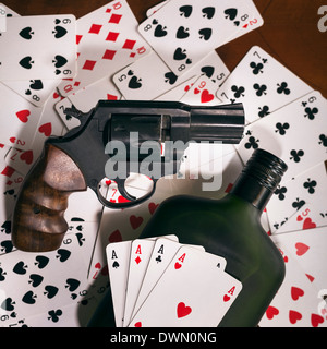 Playing cards with gun and bottle of alcohol on the table. Stock Photo