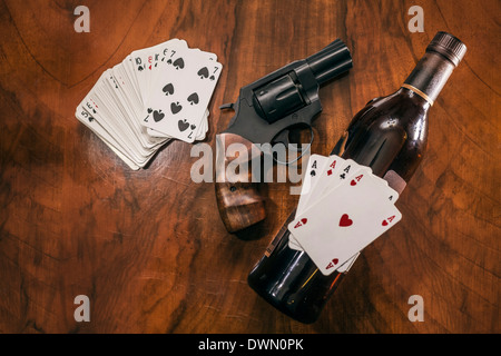 Playing cards with gun and bottle of alcohol on the table. Stock Photo