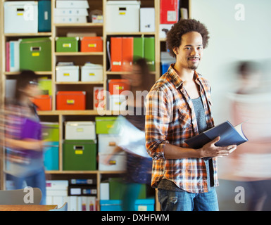 Portrait of casual businessman with co-workers rushing by in background Stock Photo