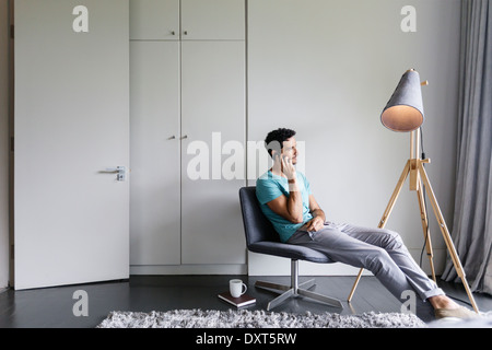 Man talking on cell phone in living room Stock Photo