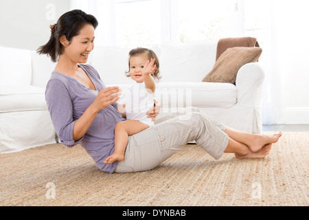 Mother playing with baby girl in living room Stock Photo