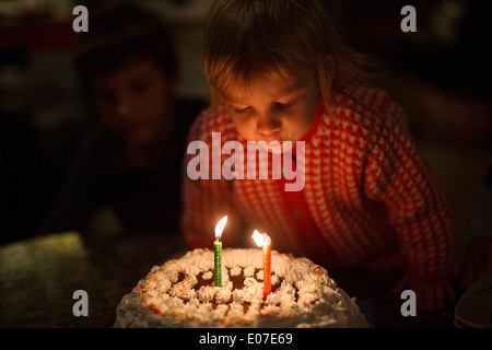 Little girl blowing out birthday candles on cake Stock Photo