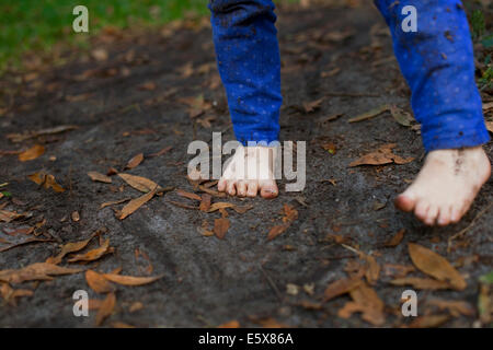 Muddy feet of four year old girl standing in garden soil Stock Photo