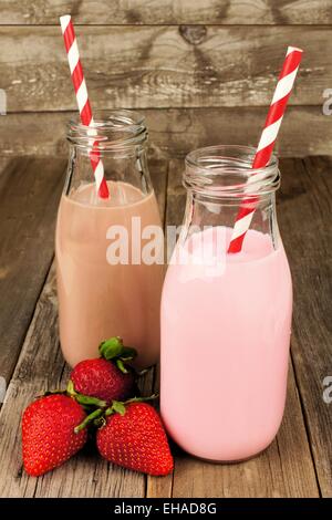 Strawberry and chocolate milk in traditional bottles with straws on old wood background Stock Photo