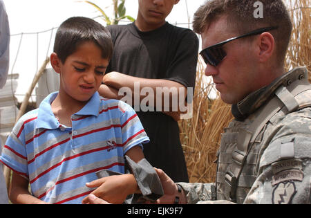 U.S. Army Sergeant Matthew Ashmead, a Combat Medic assigned to C Company, 3rd Battalion, 509th Parachute Regiment C-3/509th PIR, 4th Brigade Combat Team Airborne, 25th Infantry Division Light, measures the forearm of a local boy for a splint,  during a patrol near Tounis, North Babil, Iraq, June 28, 2007. Soldiers from C-3/509th PIR are conducting a patrol searching for evidence around the point of origin of a rocket attack on Forward Operations Base Kalsu.   Staff Sgt. Sean A. FoleyReleased Stock Photo