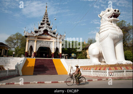 A woman cycles past the entrance steps to Mandalay Hill in Mandalay Myanmar Stock Photo