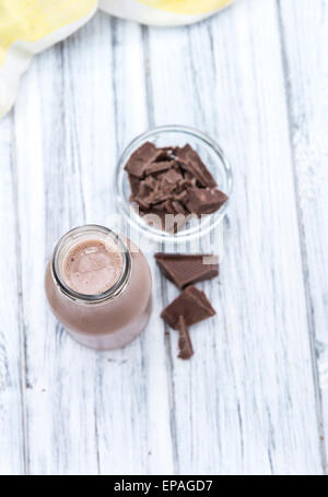 Chocolate Milk in a small bottle (on bright wooden background) Stock Photo