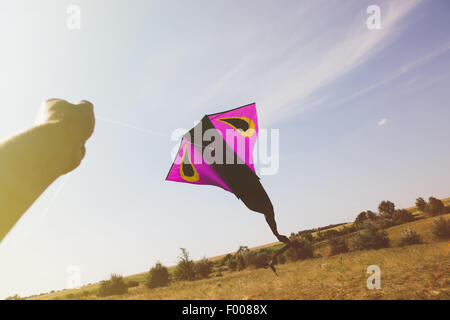 Hand holding a kite against the sky, tinted photo Stock Photo