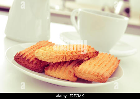 closeup of a plate with a pile of homemade biscuits and a cup of coffee or tea on the kitchen table Stock Photo