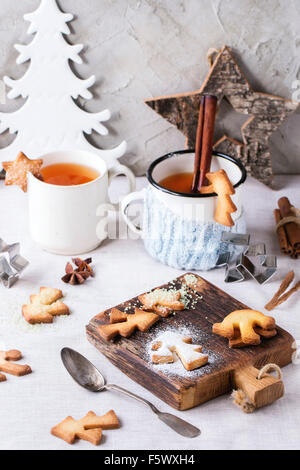 Shortbread Christmas cookies for cups, two cups of hot tea and sugar powder over table with white tablecloth with Christmas deco Stock Photo