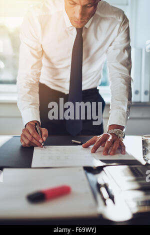 Business man closing a deal signing documents at desk in office wearing white shirt and tie Stock Photo