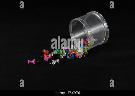 Fallen container of push pins against a black background Stock Photo