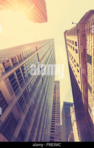 Retro stylized photo of skyscrapers in Manhattan at sunset with lens flare effect, New York City, USA. Stock Photo