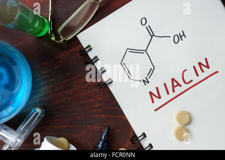 Notepad with chemical formula of  Niacin (vitamin b3) on the wooden table. Stock Photo