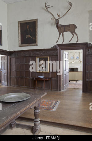 The Hall at Chastleton House, Oxfordshire. The deer painting above the door combines the antlers of a North American Caribou with a wooden head and painted body. The house was built between 1607 and 1612, and the oak panelling is also of the 1600s. Stock Photo