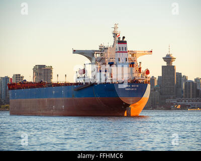 Bulk carrier 'Alpha Faith' (2008) awaits loading or unloading in Vancouver Harbour in front of Vancouver skyline. Stock Photo