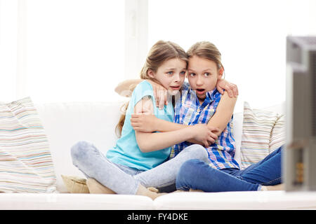 scared little girls watching horror on tv at home Stock Photo