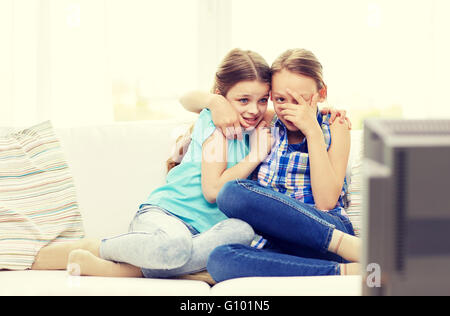 scared little girls watching horror on tv at home Stock Photo