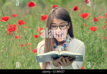 Teenage girl read a book in poppy field Stock Photo