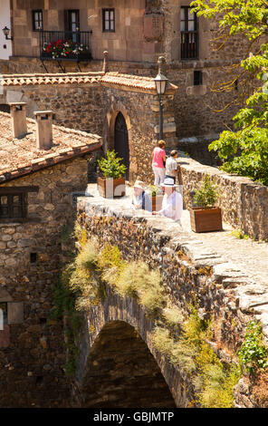 People on the medieval stone pack horse bridge of San Cayetano over the river Deva in the town of Potes in the Picos de Europa Northern Spain Stock Photo