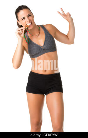 Female athlete biting her medal after winning, isolated in white Stock Photo