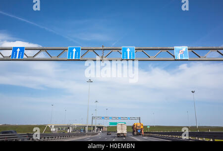 Wide highway equipment, blue road signs with white arrows shows direction of movement over traffic lanes Stock Photo