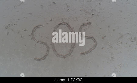 Top view photo of SOS written in sand on tropical beach. Concept photo of help emergency desperation lost and hope Stock Photo