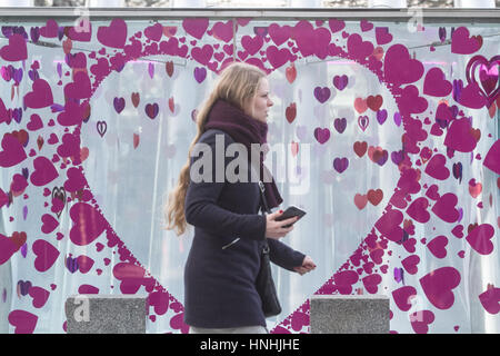 London, UK. 13th Feb, 2017. A woman walks in front of a giant heart sticker a day before Valentines day on 14th February Credit: amer ghazzal/Alamy Live News Stock Photo